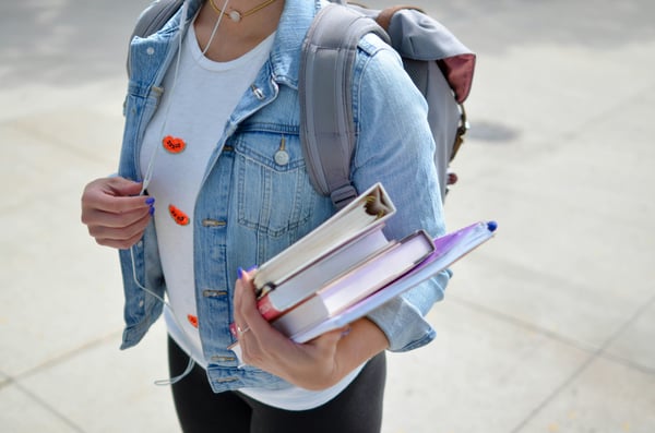 student holding books and binders